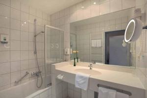 a bathroom with a sink and a shower and a mirror at Lampes Posthotel in Grünenplan