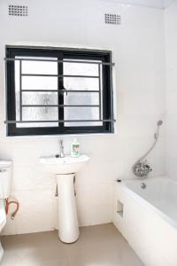a white bathroom with a sink and a bath tub at JRK Apartments & Services Limited in Lusaka