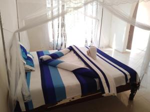 a bed with a striped blanket in a room with a window at Threshold Lodge in Kasama