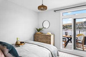 1 dormitorio con 1 cama y balcón con mesa en Harbourside 3 - Luxury Riverside Apartment en Dartmouth