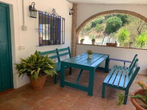 een blauwe tafel en 2 stoelen op een patio bij Casa Rural Los Almendros in Málaga