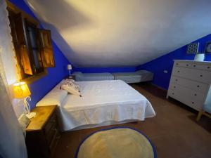 1 dormitorio azul con 1 cama y vestidor en Casa Rural Los Almendros, en Málaga