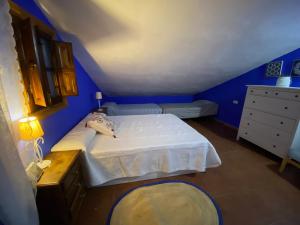 a blue bedroom with a bed and a dresser at Casa Rural Los Almendros in Málaga