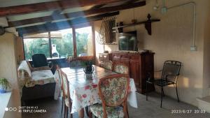 - un salon avec une table, des chaises et une télévision dans l'établissement Case vacanze Corrado 2, à La Capriola