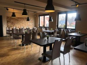 a dining room with tables and chairs and windows at Bestwaner Hotel in Bestensee