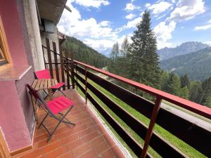 a balcony with two chairs and a view of the mountains at Il nido dei gufi in Falcade