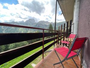 two chairs on a balcony with a view of mountains at Il nido dei gufi in Falcade