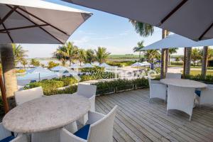 een patio met witte stoelen, tafels en parasols bij Casa com 4 suítes em Riviera de Santa Cristina in Itaí