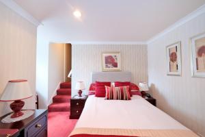 Un dormitorio con una cama con almohadas rojas y una escalera en The Jays Guest House en Aberdeen