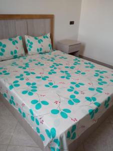 ein Bett mit einer weißen Bettdecke und blauen Blumen darauf in der Unterkunft Appartements ESSALAM 1 in El Aaiún