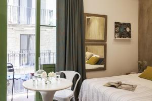 バルセロナにあるAinB Born-Dames Apartmentsのベッド2台、テーブル、窓が備わる客室です。