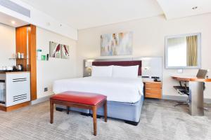 ヨハネスブルグにあるホリデー イン ヨハネスブルグ ローズバンクのベッドとデスクが備わるホテルルームです。