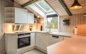 una cocina con armarios blancos y una ventana en Stunning Home In Blvand With Sauna, en Blåvand