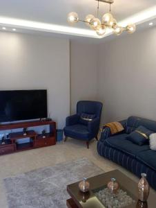 a living room with two blue couches and a tv at بيفرلي هيلز ويست تاون الشيخ زايد in Sheikh Zayed