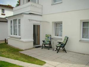 2 Stühle und ein Tisch außerhalb eines weißen Hauses in der Unterkunft Ferienwohnungen Mülling in Heringsdorf