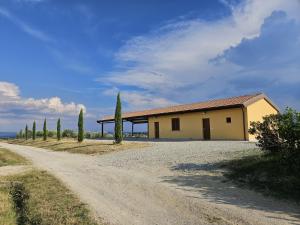a house on a gravel road with cypress trees at Agriturismo Podere Casa al Vento in Montepulciano