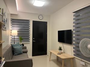 ein Wohnzimmer mit einem Sofa und einer Uhr an der Wand in der Unterkunft Mactan Cebu Guesthouse - perfect for families & friends - book now & save! in Cogon