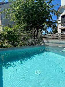 uma piscina de água azul em frente a uma casa em Proche Paris et Disney, maison avec piscine sauna em Sucy-en-Brie