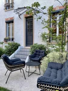 um grupo de cadeiras e uma mesa em frente a um edifício em Proche Paris et Disney, maison avec piscine sauna em Sucy-en-Brie
