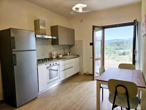 a kitchen with a refrigerator and a table with chairs at Agriturismo Podere Casa al Vento in Montepulciano