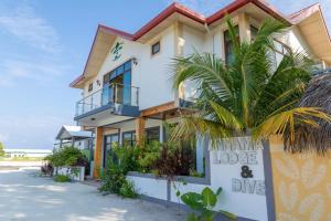 a house on the beach with a palm tree in front at Annama Lodge and Dive in Hoarafushi