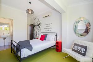 a bedroom with a bed and a chair and a clock at Times Square Terrace - Vibrant Charm in Newy's Heart in Newcastle
