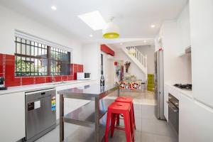 a kitchen with red cabinets and a red stool at Times Square Terrace - Vibrant Charm in Newy's Heart in Newcastle
