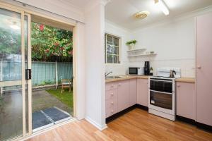 cocina con armarios blancos y ventana grande en Tighes Hill Hideaway - Alfresco Living by the Park, en Newcastle