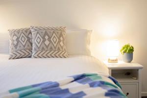 1 cama con 2 almohadas y mesa con lámpara en Tighes Hill Hideaway - Alfresco Living by the Park en Newcastle