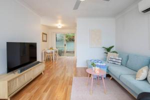 a living room with a blue couch and a flat screen tv at Tighes Hill Hideaway - Alfresco Living by the Park in Newcastle