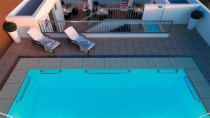 a blue swimming pool with two chairs and a table at Edificio Bulnes Iquique doble in Iquique