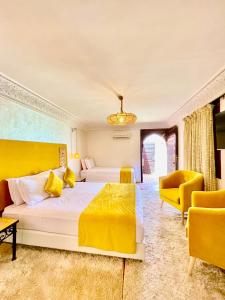 um quarto com uma cama grande e 2 cadeiras amarelas em Riad Al Wafaa em Marrakech