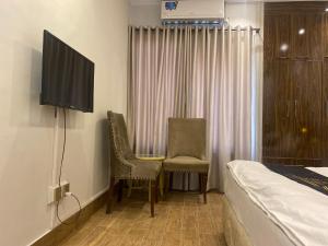 1 dormitorio con 1 cama, 2 sillas y TV en comfort you deserve, en Islamabad