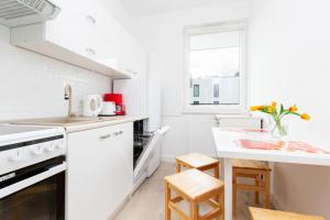 a kitchen with white appliances and a white table at Apartment Harmonia Oliwska by Renters in Gdańsk