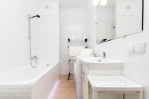 a white bathroom with two sinks and a shower at Apartment Harmonia Oliwska by Renters in Gdańsk