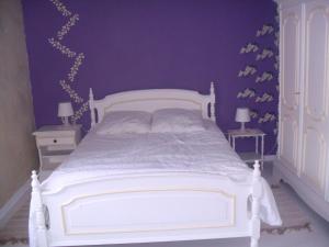 sypialnia z białym łóżkiem i fioletową ścianą w obiekcie Gîte des peupliers, gîte à la ferme 