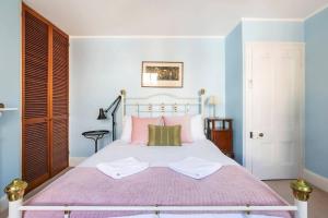 una camera da letto con un letto bianco con cuscini rosa e verdi di Elegant Vintage Terrace with Harbour Bridge Views a Sydney