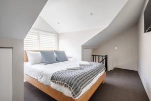 a white bedroom with a bed with blue pillows at Local's Corner - Boutique Living by Bondi Beach in Sydney
