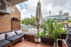 a balcony with a couch and an umbrella at Harbourside at Woolloomooloo with Balcony Views in Sydney