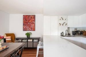 a kitchen with white cabinets and a wooden table at Harbourside at Woolloomooloo with Balcony Views in Sydney