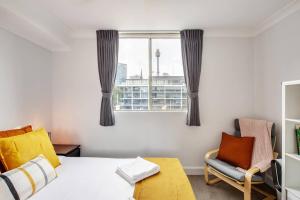 a bedroom with a bed and a chair and a window at Harbourside at Woolloomooloo with Balcony Views in Sydney