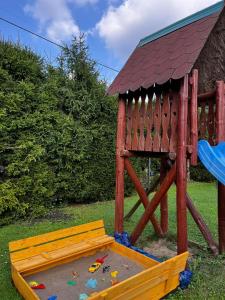 um parque infantil com uma estrutura de jogos de madeira na relva em Rajsko em Polańczyk