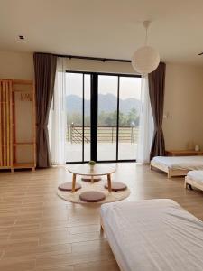um quarto com 2 camas, uma mesa e uma grande janela em Chacha Tyme Pool Villa Khaoyai em Wangkata