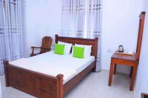 ein Schlafzimmer mit einem Bett mit grünen Kissen und einem Tisch in der Unterkunft Rock Edge Residence in Kandy