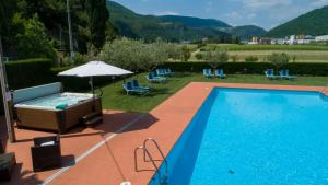 een zwembad met een hot tub en een parasol bij Hotel La Pergola in Grezzana