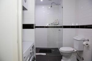 a white bathroom with a toilet and a shower at Loft-Style Living - Sophisticated Urban Retreat in Sydney