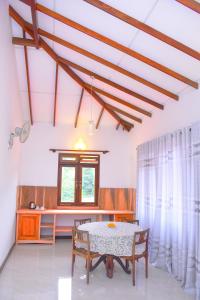 ein Esszimmer mit einem Tisch, Stühlen und einem Fenster in der Unterkunft Rock Edge Residence in Kandy