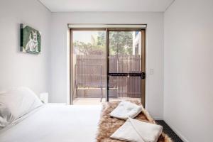 a bedroom with a bed with white sheets and a window at 'The Patio' Live like a Local in Spacious Comfort in Sydney