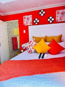 a red bedroom with a bed with colorful pillows at Duvha Guesthouse in Graskop
