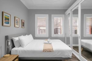 een witte slaapkamer met een groot bed en ramen bij 'Beachside Bliss' Heart of the Coastal Lifestyle in Sydney